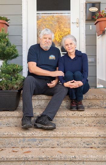 an older couple sitting on stairs outside their front door